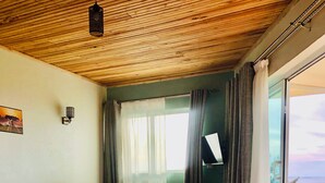 A bedroom with a bed, a bedside table, a window with curtains, and a view of the outside. - The address resort (Bugala Island)