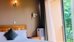 A bedroom with a wooden ceiling, a bed with white bedding, a bedside table, a wall-mounted phone, and a window with curtains. - The address resort (Bugala Island)