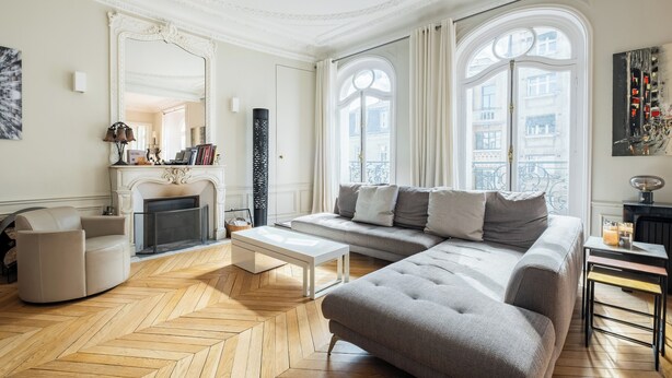 A spacious living room with a large sofa, a coffee table, and a fireplace. - Sun-drenched Sophistication, by Veeve (Paris)