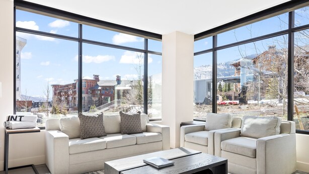 A modern living room with large windows, a sofa set, and a coffee table.