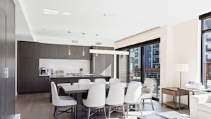 A modern kitchen with a dining area, large windows, and a view of the city.