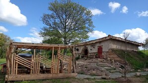 A rustic wooden structure with a partially constructed roof, a small table, and a bench.