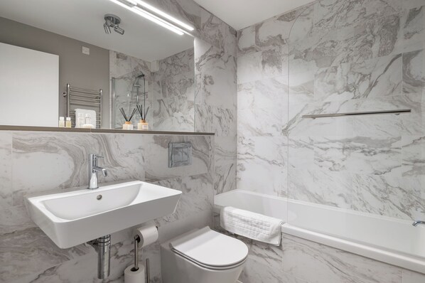 Un baño moderno con lavamanos, inodoro y bañera blancos.
