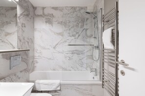 Enjoy a relaxing soak in the spacious bathtub and glass-enclosed shower area.