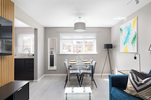 Relax in this stylish living space with a dining area, featuring a large window, comfortable sofa, and modern dining table.