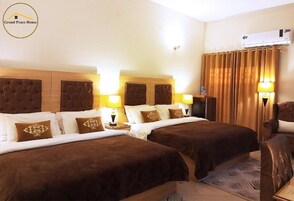 A hotel room with two beds, a wooden headboard, and a large window with curtains.