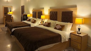 Una habitación de hotel con dos camas, lámparas de noche, un escritorio y un espejo.