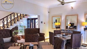 Un amplio salón con escaleras, sofás de cuero, una mesa de comedor y un ventilador de techo.