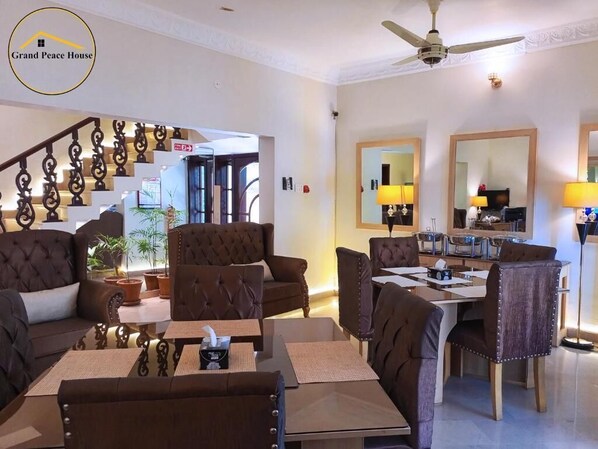 A spacious living area with a staircase, leather sofas, a dining table, and a ceiling fan.