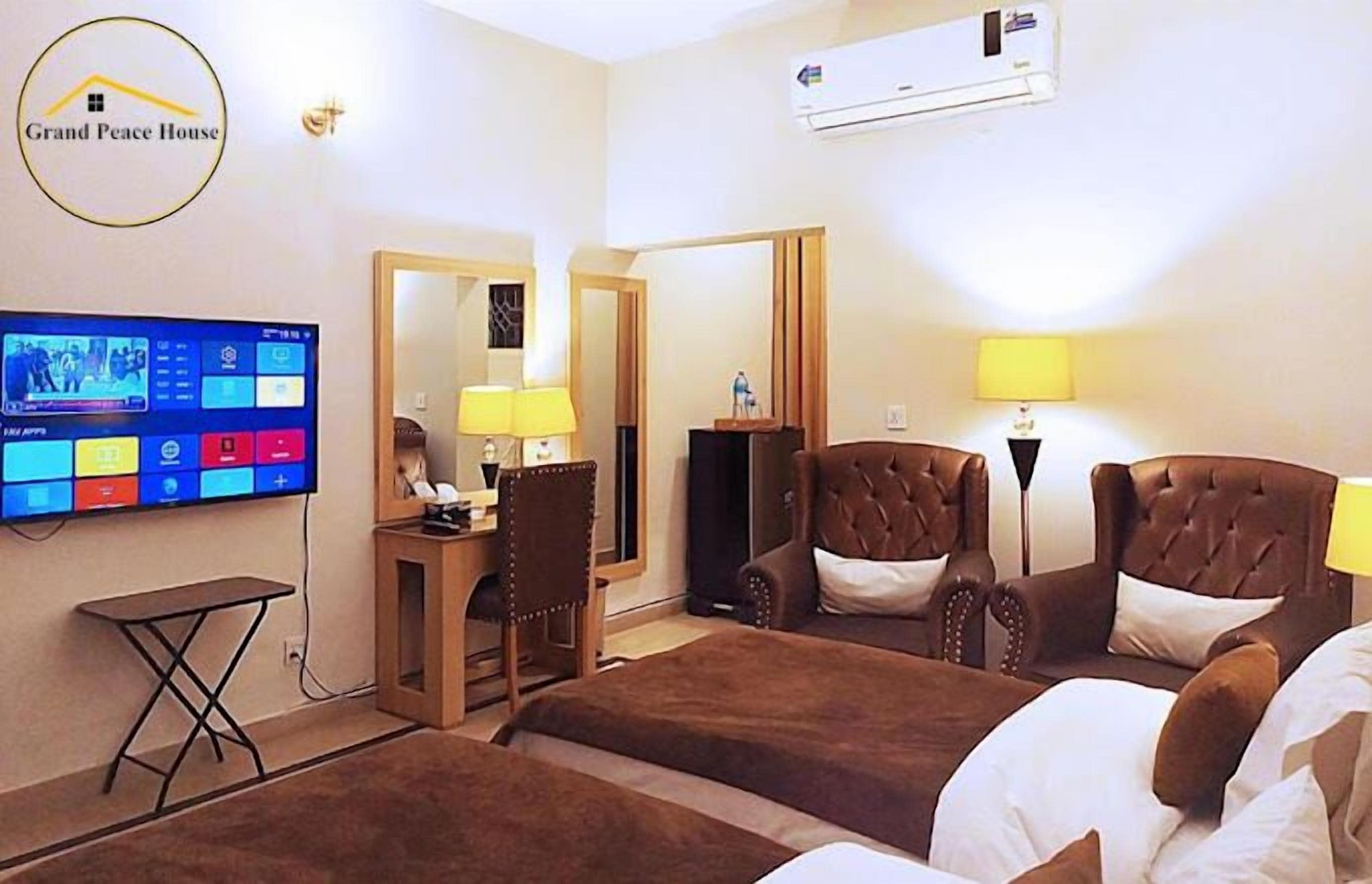A hotel room with a bed, a desk, a chair, a TV, and an air conditioning unit.