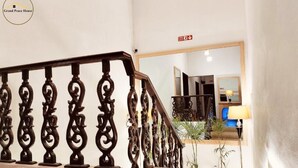 Una amplia escalera con barandales de madera decorados que conduce a un cuarto con un espejo grande y una lámpara.