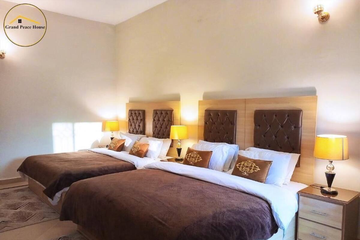 Ein Hotelzimmer mit zwei Betten, einem Nachttisch mit Lampe und einer Wandleuchte.