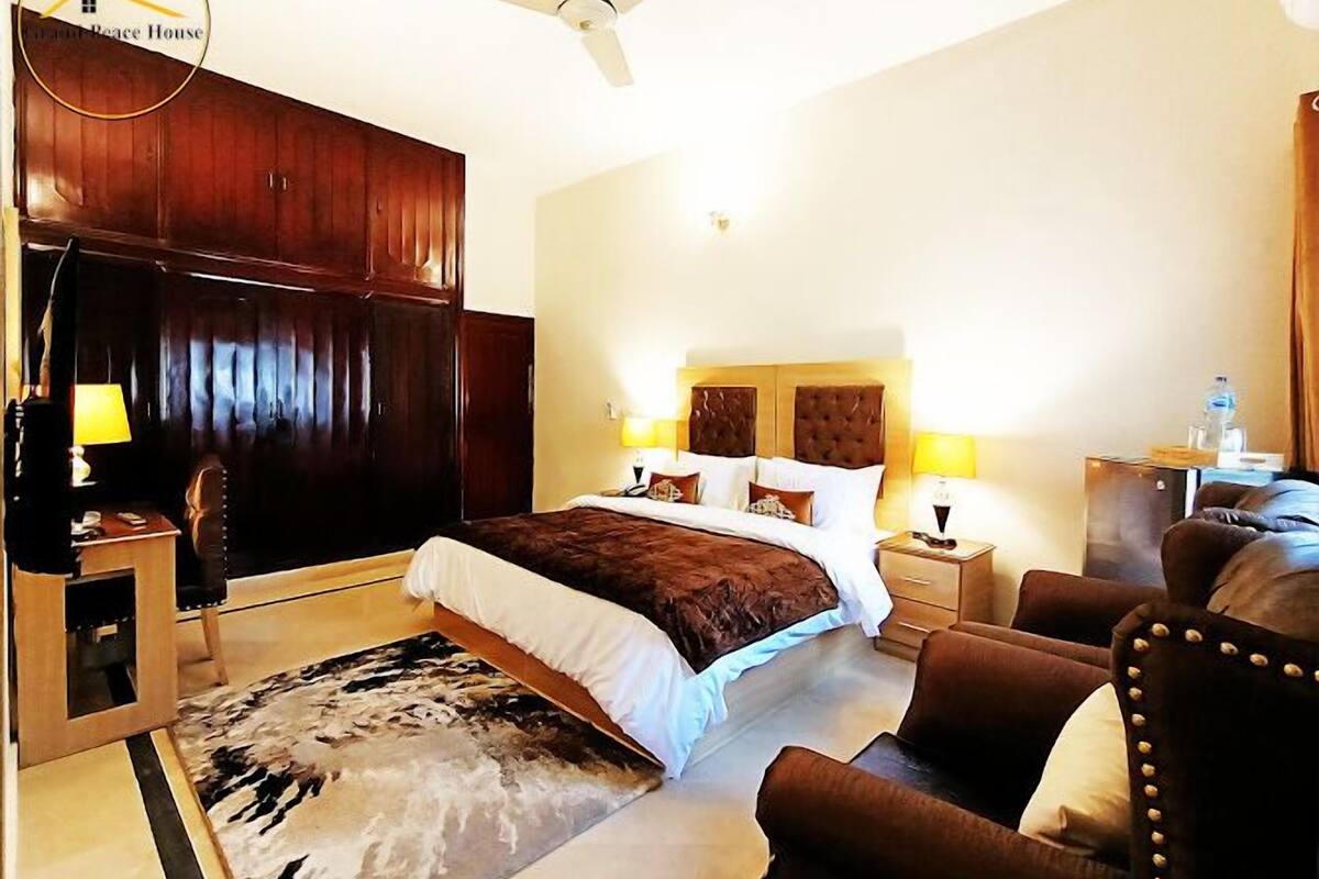 Ein Hotelzimmer mit einem großen Bett, einer Sitzecke mit einer Couch, einem Schreibtisch und einem Kleiderschrank.