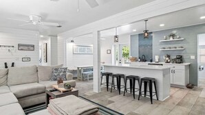 A modern living room with a sofa, coffee table, and a kitchen area with a bar stool. - Somewhere To Beach - Jacksonville Beach, Florida (Jacksonville Beach)