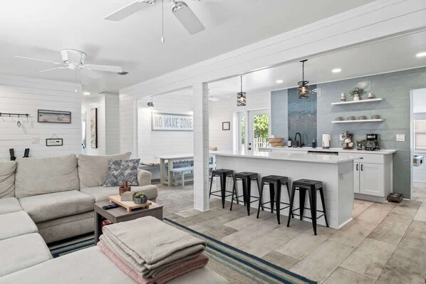 A modern living room with a sofa, coffee table, and a kitchen area with a bar stool.