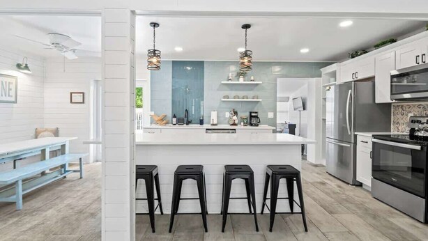 A modern kitchen with a central island, bar stools, a refrigerator, and a stove. - Somewhere To Beach - Jacksonville Beach, Florida (Jacksonville Beach)
