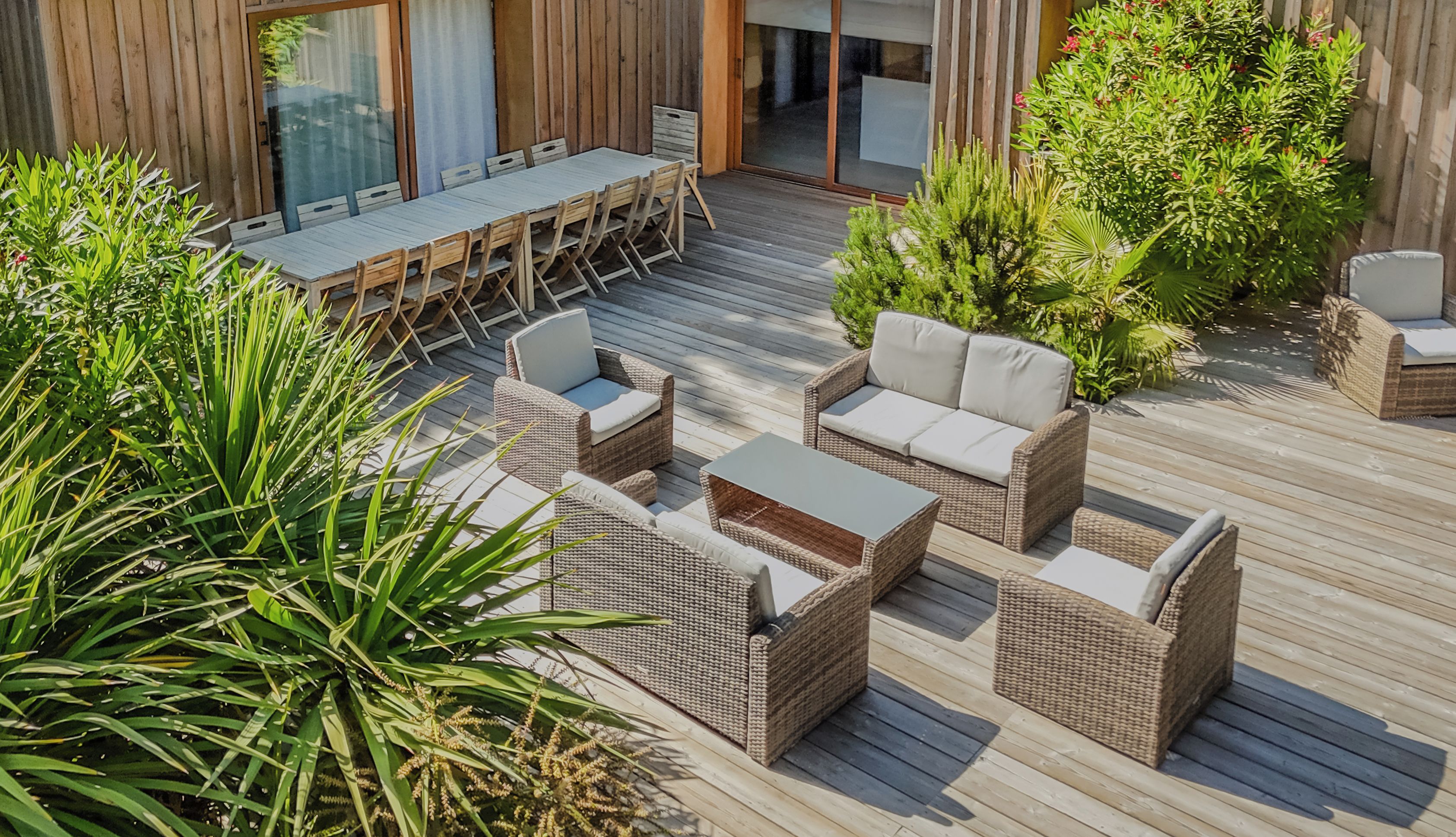 An outdoor patio with wicker furniture, a dining table, and chairs.