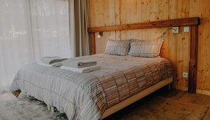 Een bed met een gestreept laken, twee kussens en opgevouwen handdoeken.