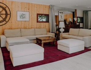 A living room with a wooden wall, a sofa set, a coffee table, and a red rug. - Villa à la Pointe du Cap Ferret (Lège-Cap-Ferret)