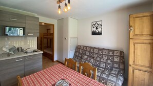 Um espaço compacto com cozinha compacta, mesa de jantar, sofá e armário de madeira.