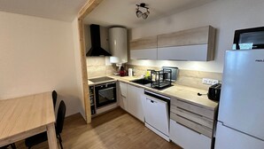 A compact kitchen with a wooden table, a built-in oven, a dishwasher, and a microwave.