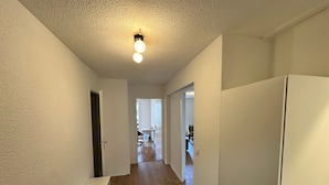 A hallway with a ceiling fan, a white door, and a white refrigerator.