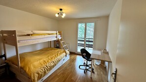 A room with a bunk bed, a desk, and a chair.