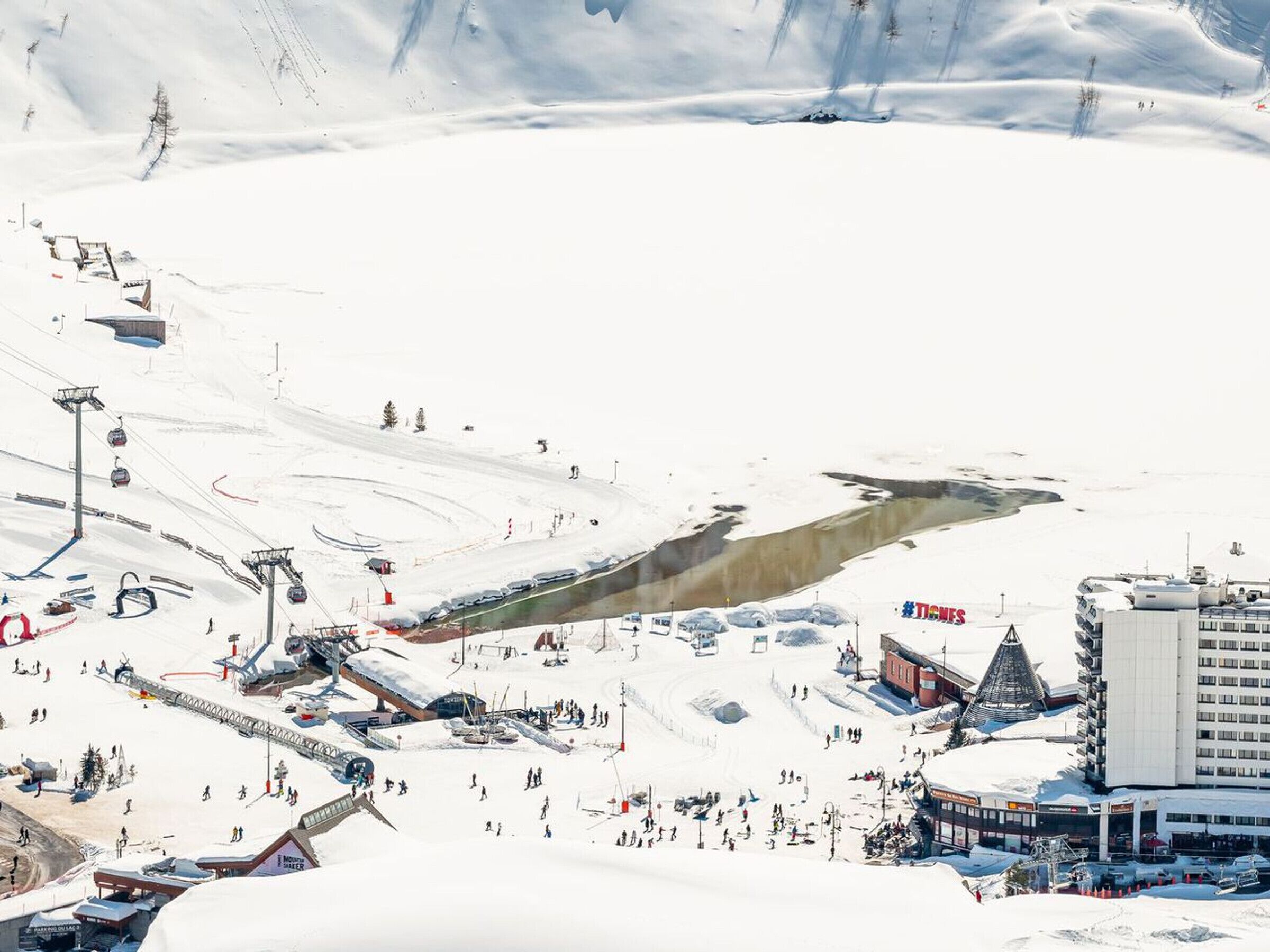 A ski resort with a ski lift, buildings, and a large snow-covered area.