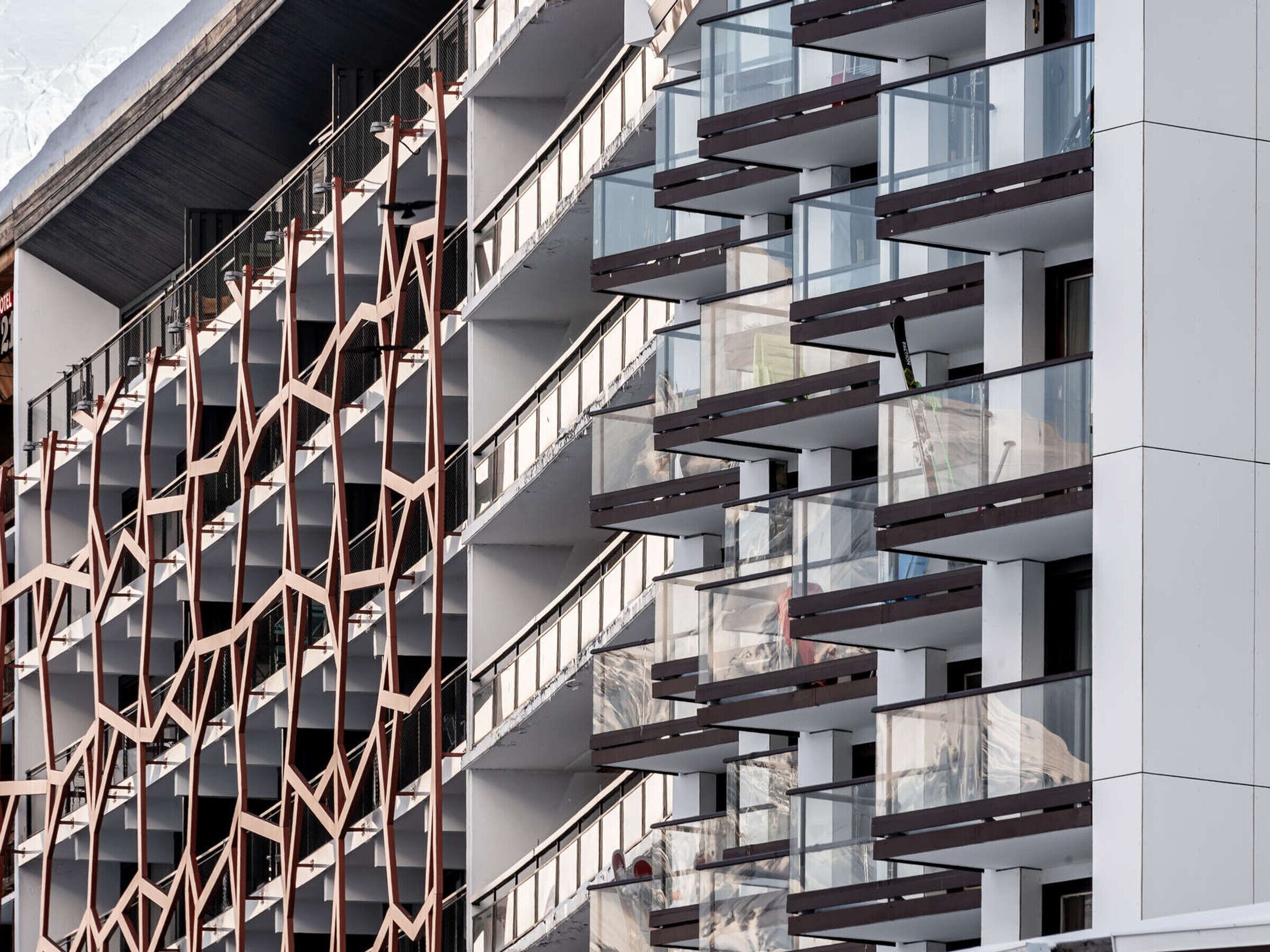 A multi-story building with a modern architectural design, featuring a series of balconies and a geometric facade.