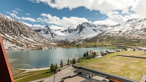 Paisaje montañoso con un lago, edificios y cielo despejado.