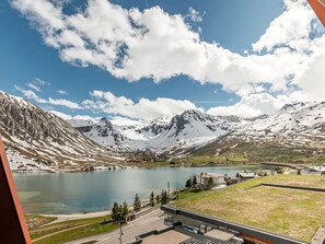 Un paysage montagneux avec un lac, des bâtiments et un ciel dégagé.