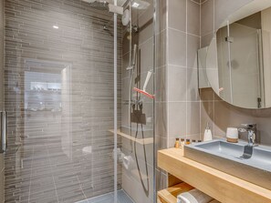 Une salle de bain moderne avec une douche à parois de verre, un meuble-lavabo en bois et un grand miroir.