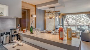 Una cocina moderna con cafetera integrada, una botella de vino y un juego de copas sobre la encimera.