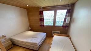 A small, cozy room with a single bed, a nightstand, a lamp, and a window with curtains. - Functional apartment in Châtel center, near ski lifts (Châtel)