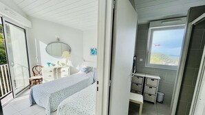 A bedroom with two beds, a dresser, a chair, a mirror, and a window with a view.