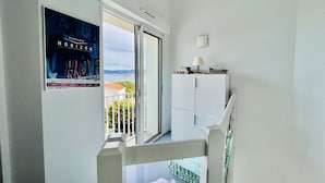 A balcony with a view of the city, a white cabinet, and a poster on the wall.