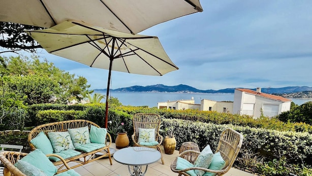 An outdoor patio with wicker furniture, a round table, and a large umbrella.