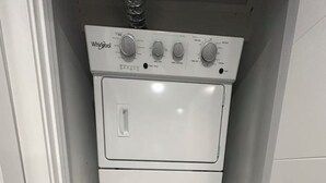 Una lavadora y secadora Whirlpool blancas y compactas en un cuarto de lavado estrecho con piso de madera.