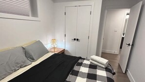 Un dormitorio con cama, mesita de noche, lámpara y armario.