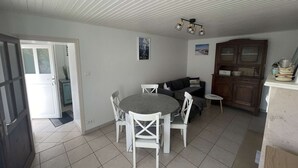 Uma área de refeições com uma mesa redonda e cadeiras, um sofá, um armário e um lustre.