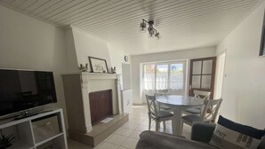 Uma sala de estar com televisão, lareira, mesa de jantar e cadeiras.