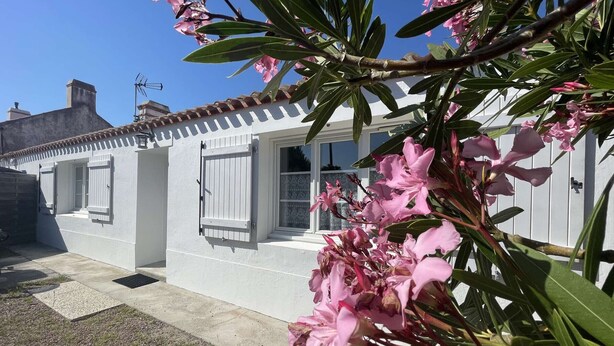 Um edifício branco com telhado em cerâmica, janela com persianas e uma porta.