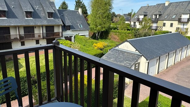 Ein Balkon mit Blick auf benachbarte Häuser und einen gepflegten Garten.