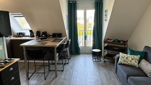Ein kompakter, moderner Raum mit Küchenzeile, Essbereich und Sofa.