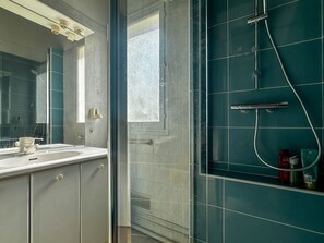 Ein Badezimmer mit Duschkabine, Waschbecken und Spiegel.