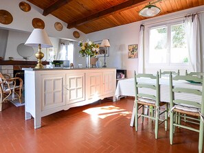A room with a wooden ceiling, a white cabinet, a bed with green headboards, and a window with curtains.