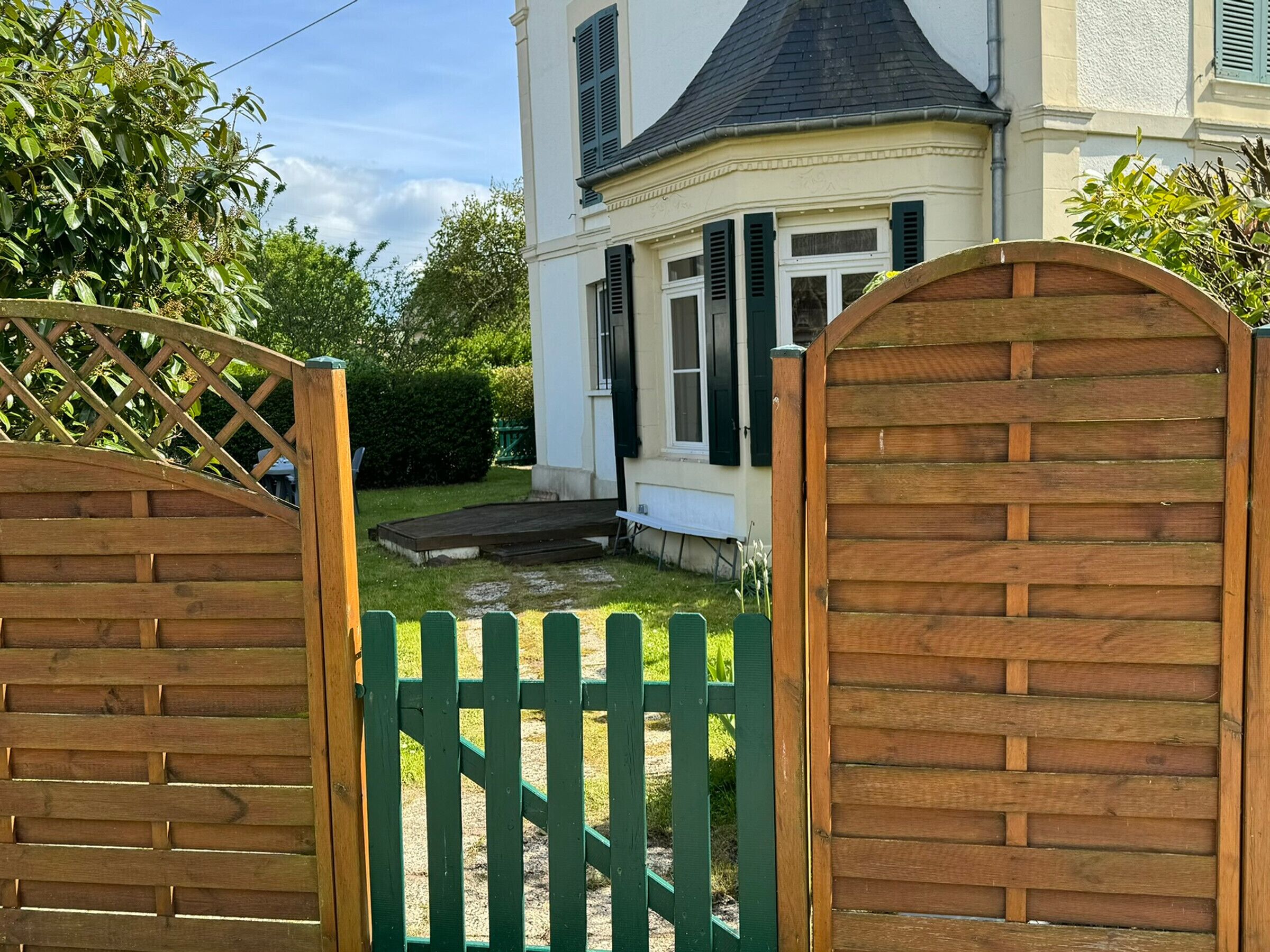 A gated entrance to a house with a wooden fence and a small garden area.