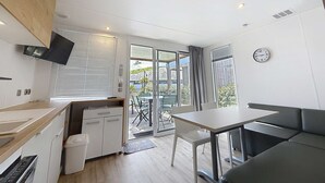 Een moderne keuken met een ingebouwde oven, een eethoek met tafel en stoelen, en een grote schuifdeur naar een terras.