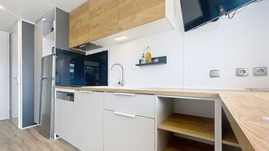 Een moderne keuken met witte kastjes, een houten aanrechtblad, een inbouwoven en een aan de muur bevestigde televisie.