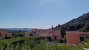Zona residencial con casas, una colina con vegetación y cielo despejado.
